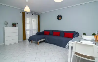 a living room with a blue couch and red pillows at Top Strip Albufeira in Albufeira