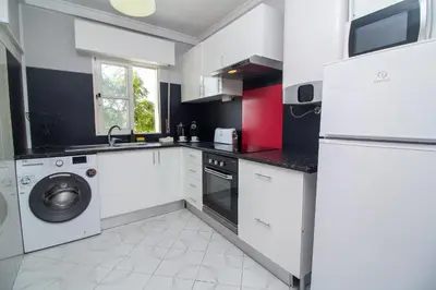 a kitchen with white cabinets and a washer and dryer at Top Strip Albufeira in Albufeira