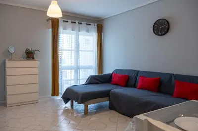 a living room with a blue couch and red pillows at Top Strip Albufeira in Albufeira