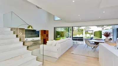 a living room with a white couch and a staircase at Villa Barinel by Cleverdetails located in a quiet and privileged area of Vilamoura in Quarteira