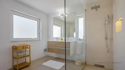 a bathroom with a shower and a sink and a mirror at Greice Homes - Villa Carob Tree in Almancil