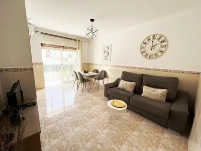 a living room with a couch and a clock on the wall at Sunny Apt - 4, Pool, Ac, Wi-fi in Olhos de Água