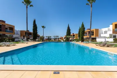 a swimming pool in a resort with palm trees at Vitismar II com piscina, jardim e garagem in Guia