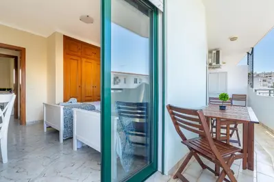 a room with a table and a chair and a kitchen at Apartamento Norte by Férias com Sol in Quarteira
