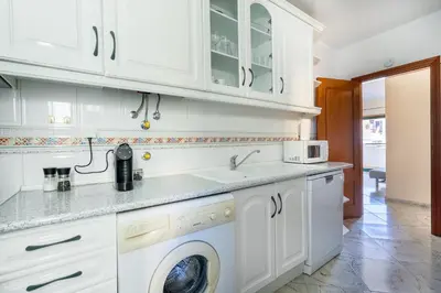 a kitchen with white cabinets and a washer and dryer at Apartamento Norte by Férias com Sol in Quarteira