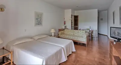 a hotel room with a bed and a table and chairs at Dom Pedro Portobelo in Quarteira
