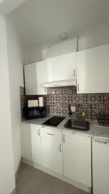 a kitchen with white cabinets and a sink at My Cozy Oura Studio in Albufeira