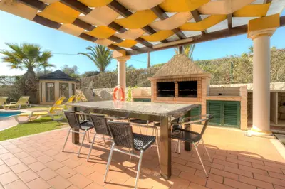 a patio with a table and chairs and a gazebo at Vivenda Alegria in Albufeira