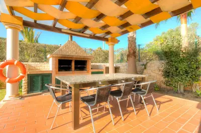 a patio with a table and chairs and a gazebo at Vivenda Alegria in Albufeira