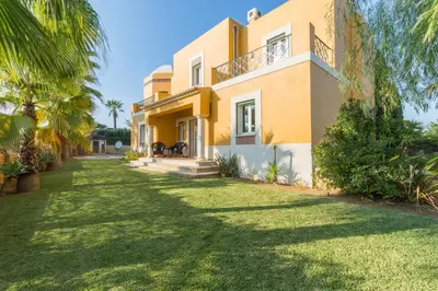 a large yellow house with a yard in front of it at Vivenda Alegria in Albufeira
