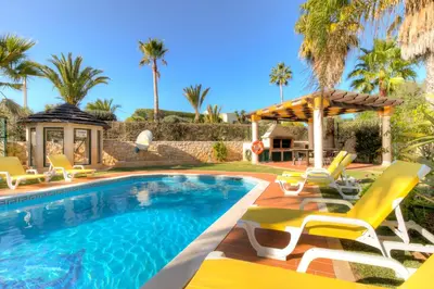 a swimming pool with chairs and an umbrella at Vivenda Alegria in Albufeira