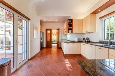 a kitchen with white cabinets and a tile floor at Villa Serena in Almancil