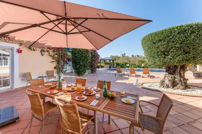 a wooden table with an umbrella on a patio at Villa Serena in Almancil