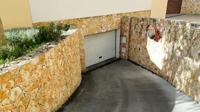 a garage with a white garage door in a stone wall at E Orada sea view historic center tennis in Albufeira