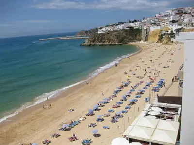 a beach with chairs and umbrellas and the ocean at Albufeira - T2 Old Town Central - 200m Beach in Albufeira