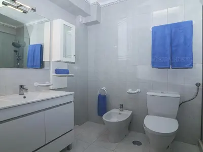 a white bathroom with a toilet and a sink at Villa Galé 600m from the beach by Interhome in Patroves