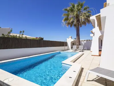 a swimming pool with a palm tree next to a house at Villa Galé 600m from the beach by Interhome in Patroves