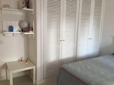 a bedroom with white closets and a bed and a table at Vilamoura Villa Alegria in Vilamoura