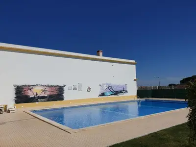 a swimming pool in front of a building with a painting at Albufeira Falesia Beach Apartment in Albufeira