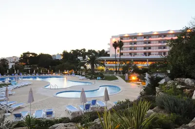 a large swimming pool with umbrellas and chairs and a hotel at INATEL Albufeira in Albufeira