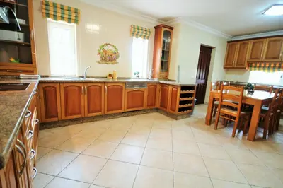 a large kitchen with wooden cabinets and a table at Villa Fonte Santa in Quarteira