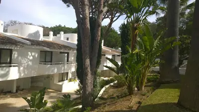 a view of a white building with palm trees at Blue&Greens Apartment in Quinta do Lago