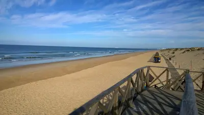 a person standing on a sandy beach near the ocean at Blue&Greens Apartment in Quinta do Lago