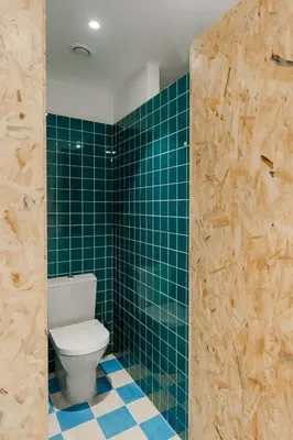 a bathroom with a toilet and green tiled walls at Hostel Conii & Suites Algarve in Quarteira