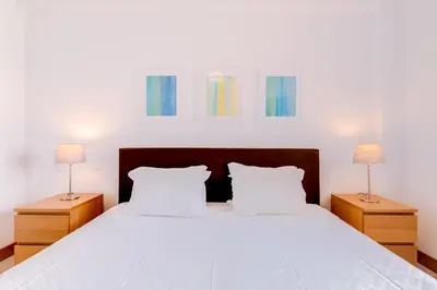 a bedroom with a large white bed with two lamps at AL- Apartamentos Novos Vista Mar in Quarteira