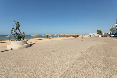 a statue on a beach next to the ocean at AL- Apartamentos Novos Vista Mar in Quarteira