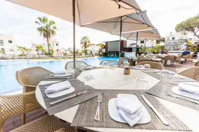 a table with a plate of food and a glass of wine at Apartamentos Honorio - Pool and Garden in Vilamoura