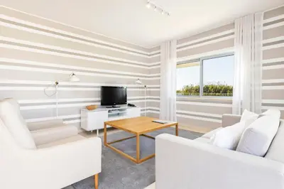 a living room with two white chairs and a television at Laguna - Vilamoura in Vilamoura