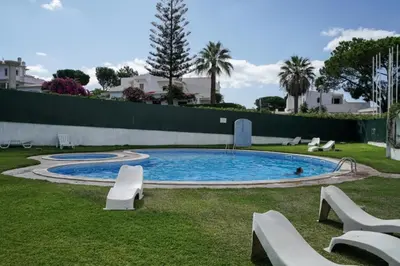 a swimming pool with white chairs in a yard at Akisol Vilamoura Star II in Quarteira