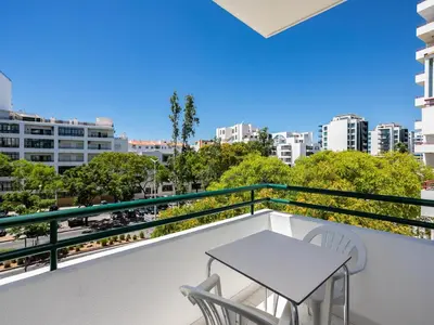 a balcony with a table and chairs and a view of the city at Akisol Quarteira Relax III in Quarteira