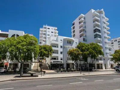 an empty street in front of a large white building at Akisol Quarteira Relax III in Quarteira