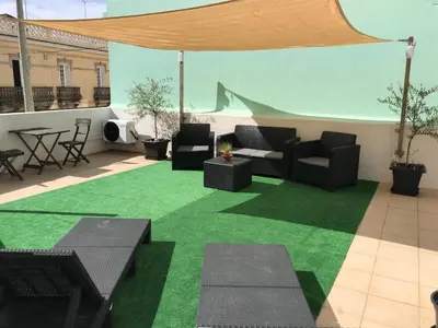 a patio with green grass and black chairs and tables at MariaHouse in Faro