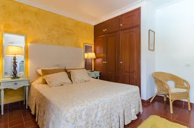 a bedroom with a bed and a chair and a mirror at Villa Casa do Sul in Albufeira