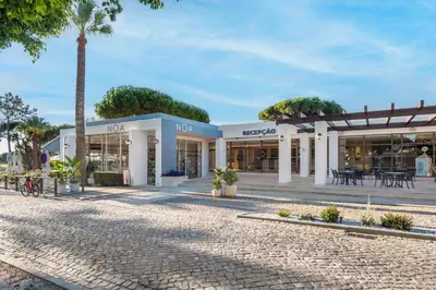 a building with a palm tree in front of it at Vilar do Golf in Quinta do Lago