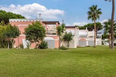 a pink house with palm trees in front of it at Vilar do Golf in Quinta do Lago