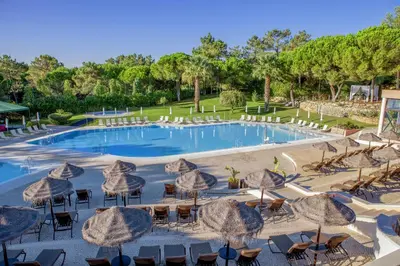 a large pool with umbrellas and tables and chairs at Vilar do Golf in Quinta do Lago