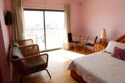 a bedroom with a bed and a chair and a table at BellaVita City Faro in Faro
