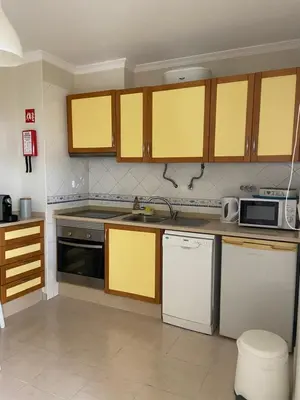a kitchen with yellow cabinets and white appliances at Moura 11 in Vilamoura