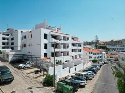 a parking lot with cars parked in front of a building at Cheerfulway Ouravista Apartamentos in Albufeira