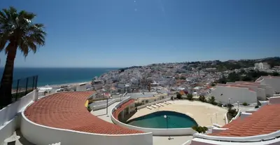 a view of a city with a swimming pool and the ocean at Apartamentos Tio Papel in Albufeira