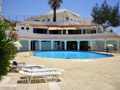 a swimming pool in front of a large building at Apartamentos Tio Papel in Albufeira