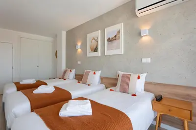 a hotel room with three beds with brown and white sheets at Hotel Made inn Faro in Faro