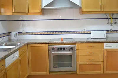 a kitchen with wooden cabinets and a stove top oven at Jardins Santa Eulalia by Garvetur in Albufeira