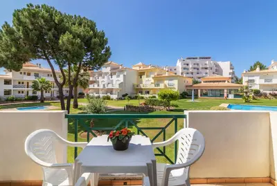 a white table and chairs on a balcony with buildings at Jardins Santa Eulalia by Garvetur in Albufeira