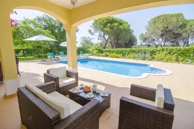 a patio with a pool with chairs and a table at Bonita in Quarteira
