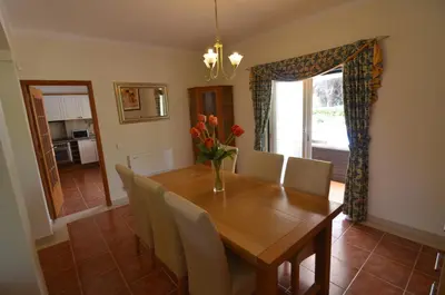 a dining room with a wooden table and chairs at Bonita in Quarteira